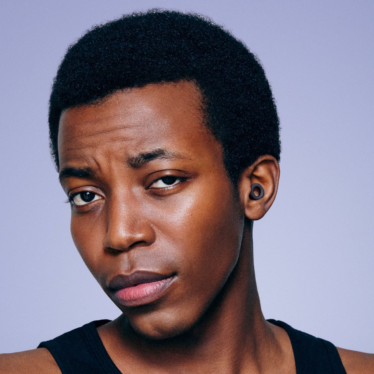 Man wearing a Black PLUGS earplug, the ring sitting in his outer ear