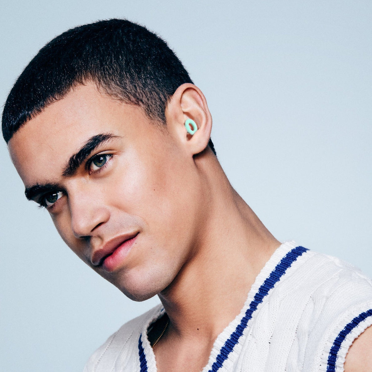 Man wearing a Mint PLUGS earplug, shown from the side
